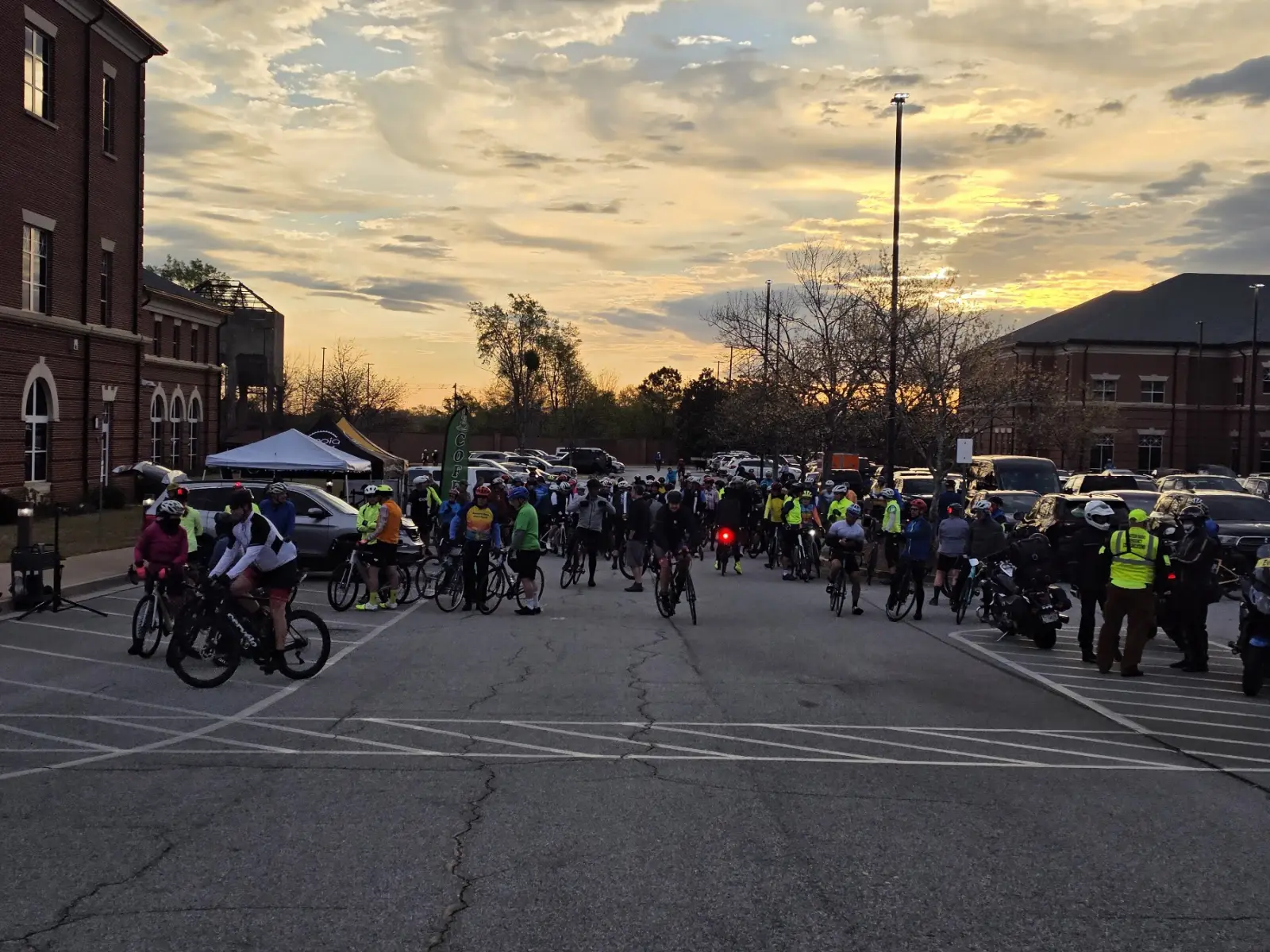 Several hundred cyclists gathered in the parking lot beside the brick Coweta County Justice Center at sunrise, with police motorcycle escorts waiting alongside them, at the 2026 Tour of Coweta.